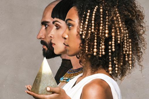 The photo shows the event subject of the opera Aida with three oriental / Egyptian-looking people, one of them holding a small pyramid made of stone in her hand
