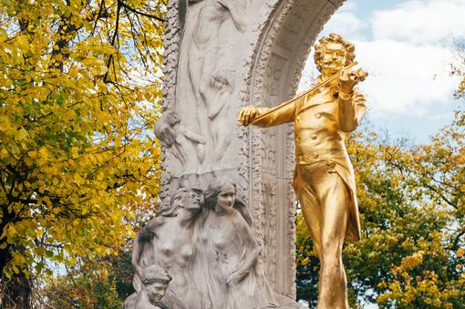 Das Foto zeigt die goldene Statue von Johann Strauss, welche Teil des Johann Strauss Denkmals im Wiener Stadtpark ist