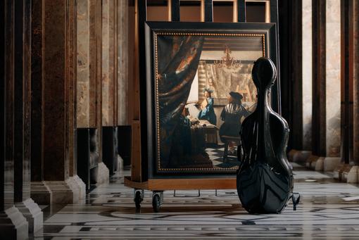 Black case of a double bass standing in front of the painting "The Painting Art" by Jan Vermeer