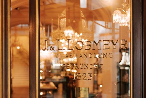 Photo of the Lobmeyr company entrance with the company name in the background various crystal chandeliers