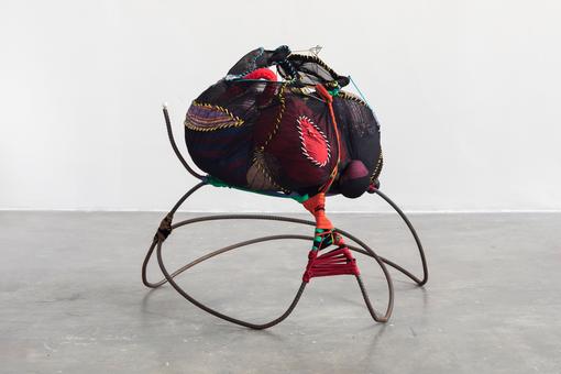 Photo of an installation showing a kind of ball of fabric and ribbons on a metal frame.