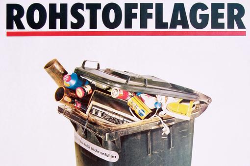 The photo shows a black garbage can overflowing with garbage, against a white background, with the black lettering Rohstofflager in capital letters above it