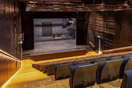 The photo shows the auditorium of the Nest, the perspective from the ascending rows of seats onto the empty stage