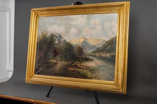 Photo of oil painting with heavy golden frame showing mountain landscape