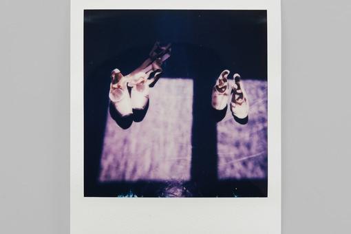 You can see a Polaroid photo showing two pairs of pink ballet shoes