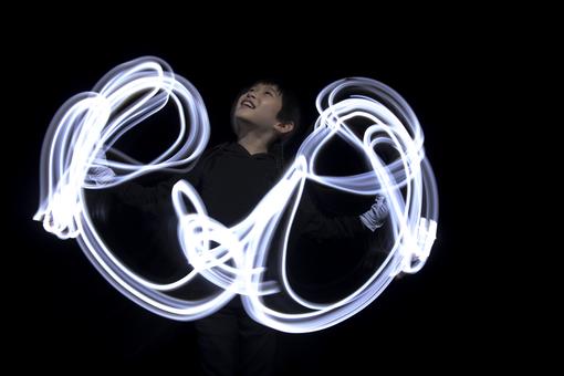 The photo shows the movement of a young Japanese woman's arms like white snakes of light against a black background