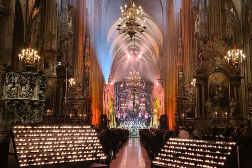 Interior view of St. Stephen's Cathedral in Vienna with festive lighting, countless glowing candles in the foreground