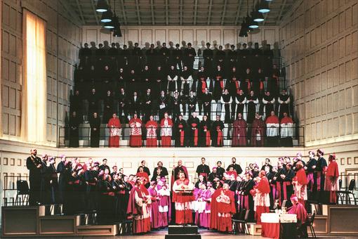 Das Szenefoto der Oper Palestriana zeigt eine Versammlung von Kardinälen und Bischöfen der katholischen Kirche im Vordergrund, im Hintergrund wie auf einer Empore steil ansteigend weitere Bischöfe und Ordensbrüder