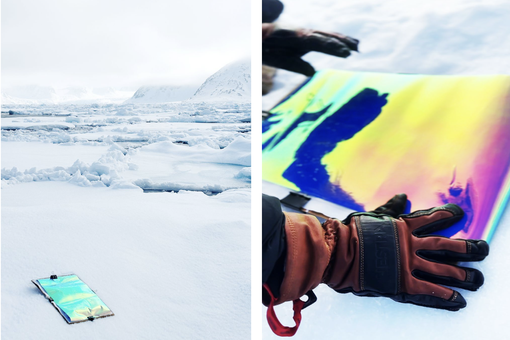 The photo shows Laure Winants' work with light and color in the Arctic. You can see a colored print held against the ice by thick red and black gloves.